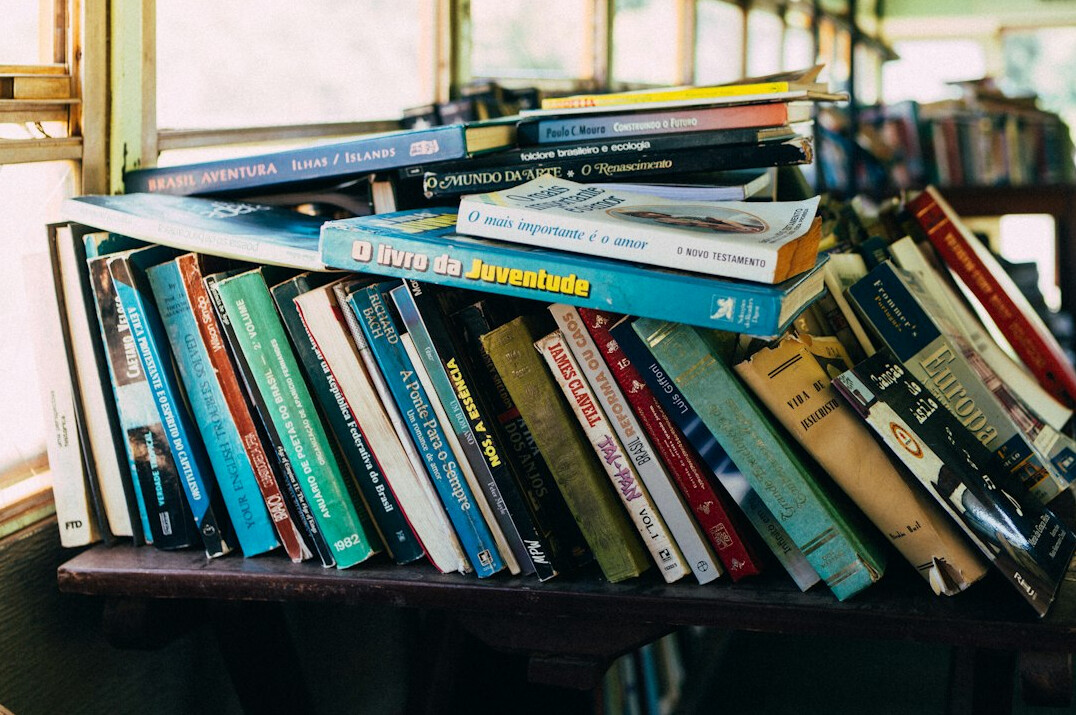 Stack of books on a wooden desk in a library